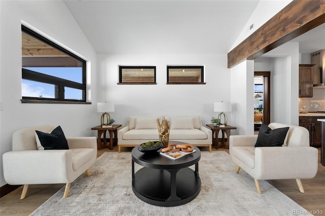 living area with visible vents, light wood-style floors, and lofted ceiling