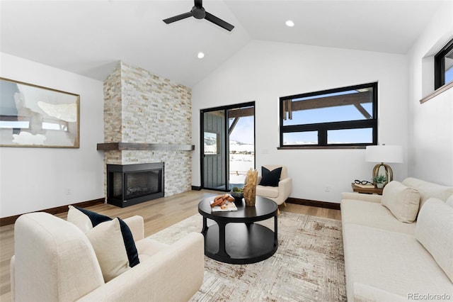 living room featuring baseboards, a ceiling fan, wood finished floors, and a fireplace