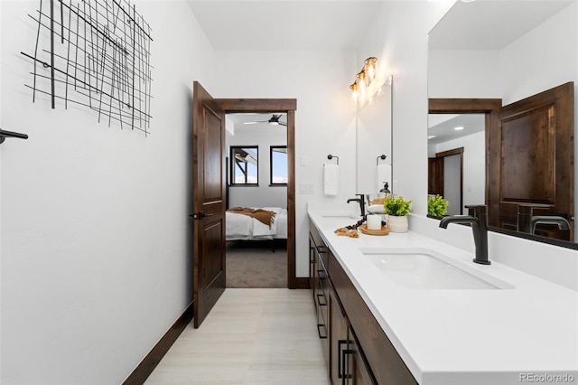 full bath featuring double vanity, ensuite bathroom, baseboards, and a sink