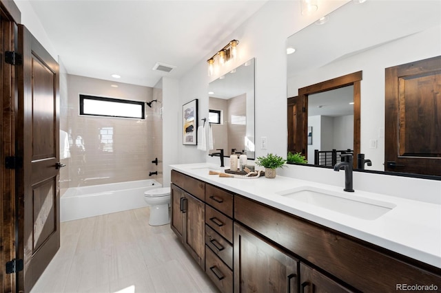 full bath with visible vents, double vanity, a sink, bathing tub / shower combination, and toilet