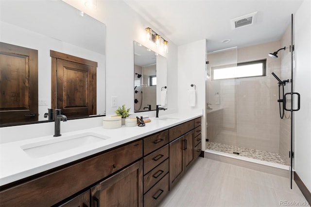 bathroom featuring a shower stall, double vanity, visible vents, and a sink