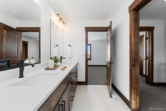 full bathroom with a sink, visible vents, baseboards, and double vanity