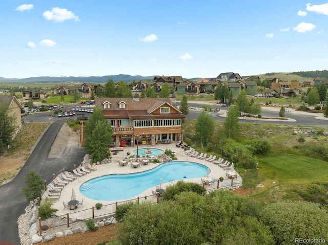 exterior space featuring fence, a patio area, a residential view, and a mountain view