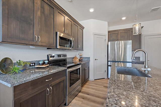 1100 Blue Bell Rd, Berthoud, CO 80513 - kitchen featuring appliances with stainless steel finishes, a sink, dark stone countertops, dark brown cabinetry, and light wood-style flooring