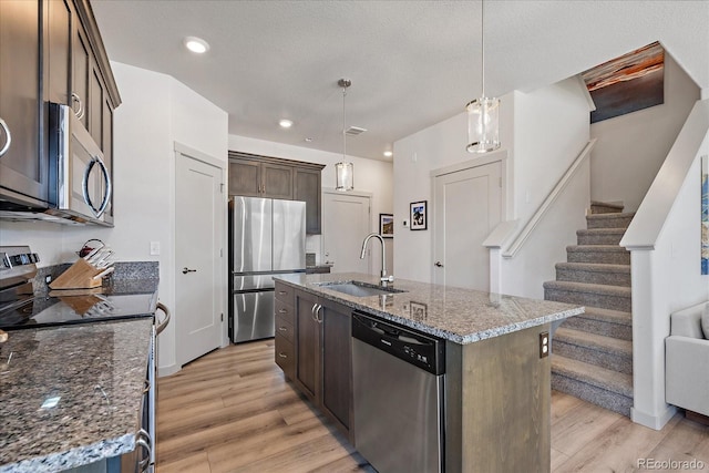 1100 Blue Bell Rd, Berthoud, CO 80513 - kitchen with appliances with stainless steel finishes, a sink, light wood-type flooring, dark brown cabinetry, and stone counters