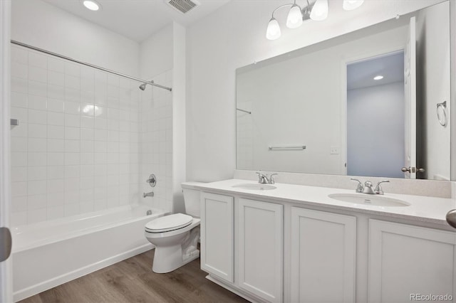 full bathroom featuring vanity, toilet, tiled shower / bath combo, and hardwood / wood-style floors