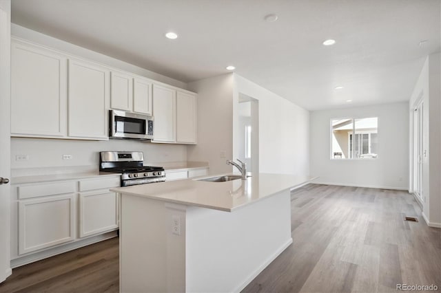 kitchen with white cabinets, appliances with stainless steel finishes, sink, and a kitchen island with sink