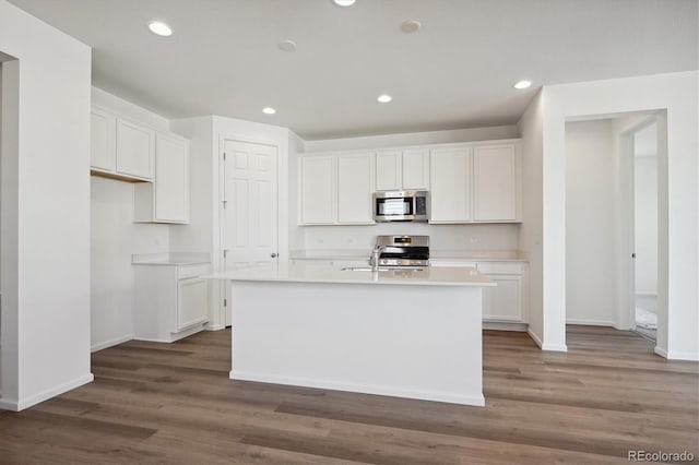 kitchen with appliances with stainless steel finishes, white cabinets, and an island with sink