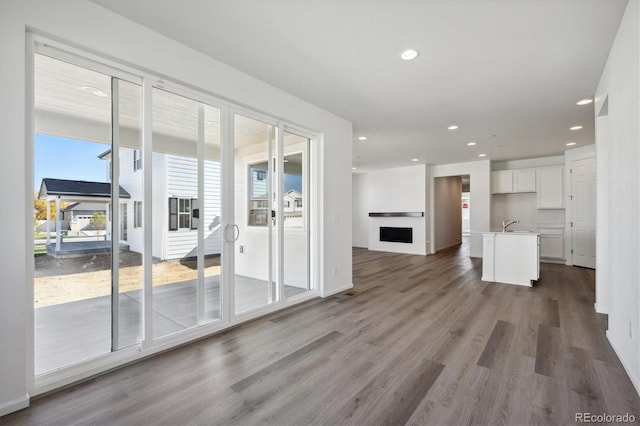 unfurnished living room featuring sink, hardwood / wood-style floors, and a healthy amount of sunlight