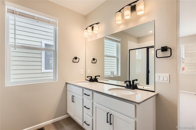 4102 Estrella St, Brighton, CO 80601 - bathroom with double vanity, a shower with shower door, and wood finished floors
