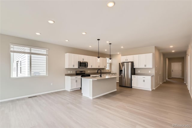 4102 Estrella St, Brighton, CO 80601 - kitchen with appliances with stainless steel finishes, an island with sink, light wood-type flooring, recessed lighting, and white cabinetry