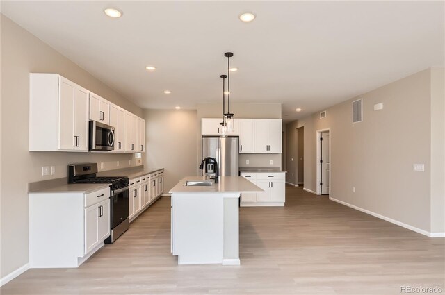 4102 Estrella St, Brighton, CO 80601 - kitchen featuring appliances with stainless steel finishes, light wood finished floors, a center island with sink, decorative light fixtures, and recessed lighting