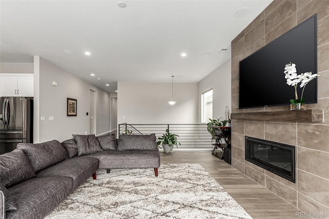 living room with a tiled fireplace, visible vents, recessed lighting, and light wood-style floors