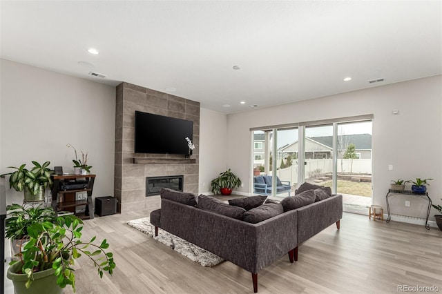 living area featuring light wood finished floors, a tile fireplace, visible vents, and recessed lighting