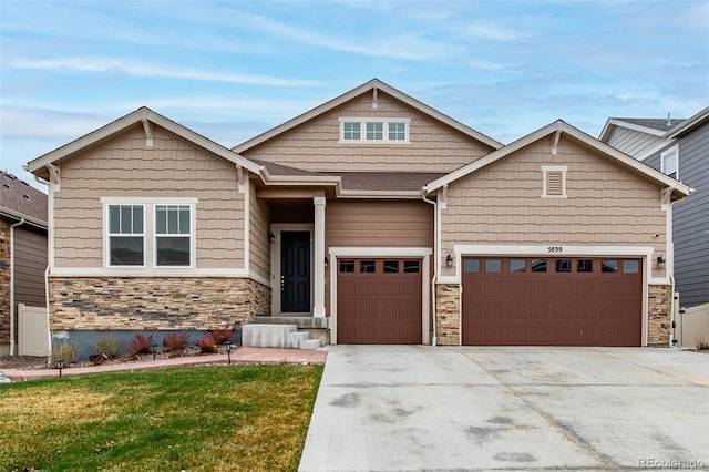 craftsman-style home with stone siding, a front lawn, driveway, and a garage
