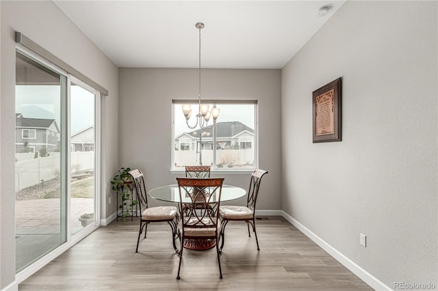 dining area featuring baseboards, a notable chandelier, and light wood finished floors