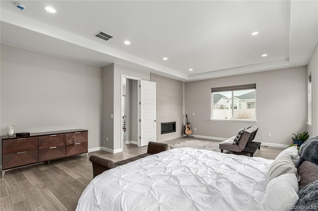 bedroom with recessed lighting, wood finished floors, visible vents, and a raised ceiling