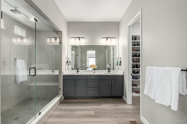 full bathroom with wood finished floors, a sink, and a stall shower