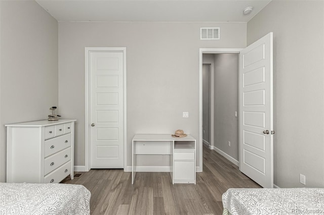 bedroom with baseboards, wood finished floors, and visible vents