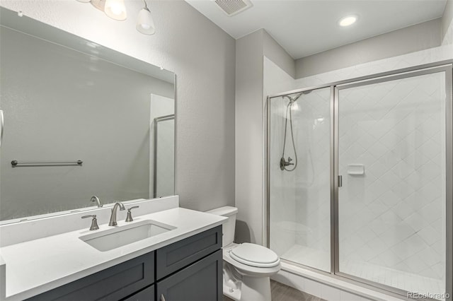 bathroom with toilet, visible vents, wood finished floors, a shower stall, and vanity