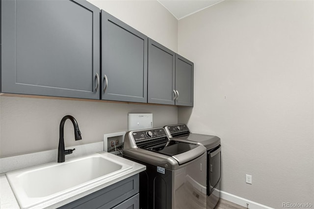 laundry area with cabinet space, baseboards, separate washer and dryer, and a sink