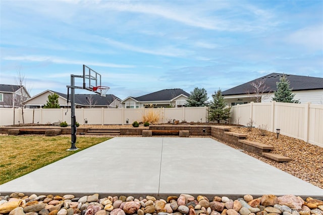 view of sport court with a lawn, a fenced backyard, basketball court, and a residential view