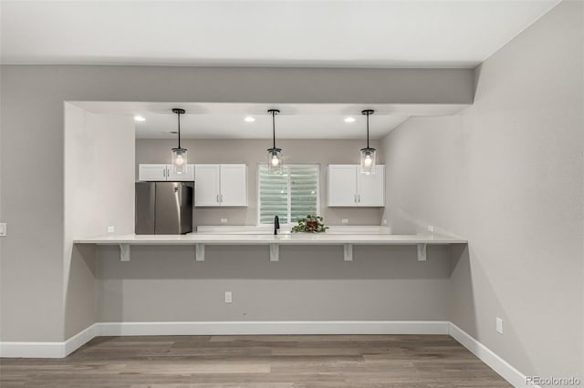 5839 Hay Market Trl, Parker, CO 80134 - kitchen featuring freestanding refrigerator, a peninsula, a kitchen bar, white cabinetry, and recessed lighting