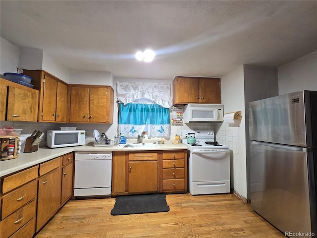 7371 Granada Rd, Denver, CO 80221 - kitchen with white appliances, brown cabinets, light wood finished floors, and a sink