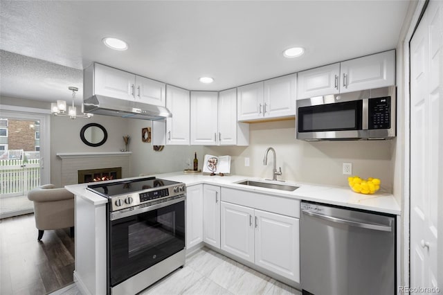 2856 S Kenton Ct, Aurora, CO 80014 - kitchen with stainless steel appliances, under cabinet range hood, a peninsula, white cabinetry, and recessed lighting