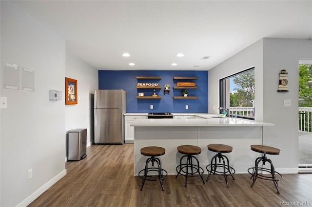 2856 S Kenton Ct, Aurora, CO 80014 - kitchen featuring appliances with stainless steel finishes, wood finished floors, recessed lighting, white cabinetry, and a kitchen bar