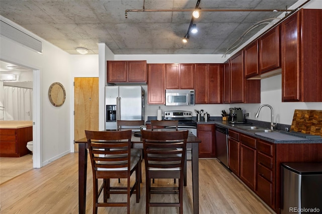 1475 Delgany St Unit 307, Denver, CO 80202 - kitchen with stainless steel appliances, light wood-style flooring, dark countertops, and reddish brown cabinets