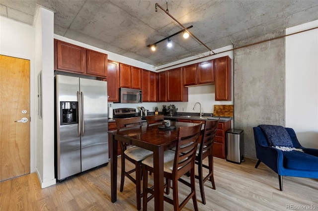 1475 Delgany St Unit 307, Denver, CO 80202 - kitchen featuring appliances with stainless steel finishes, light wood-style flooring, dark countertops, and dark brown cabinets