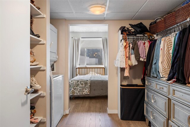 1475 Delgany St Unit 307, Denver, CO 80202 - spacious closet featuring stacked washing machine and dryer, a paneled ceiling, and wood finished floors