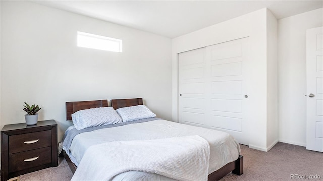 bedroom with a closet, light colored carpet, and baseboards