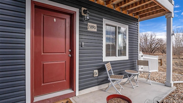 property entrance featuring covered porch and fence