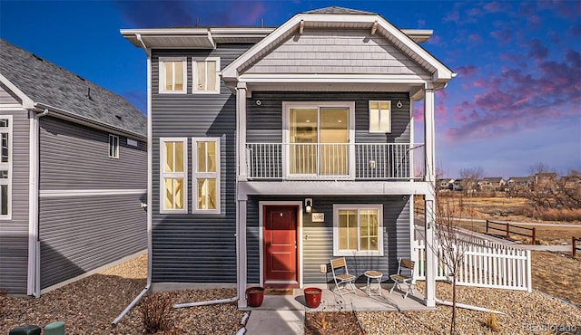 view of front of property featuring a patio area, fence, and a balcony