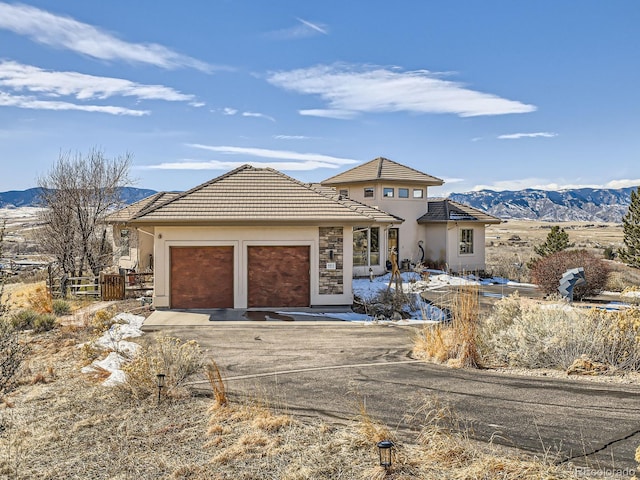 view of front of home featuring a garage, a tile roof, a mountain view, and concrete driveway