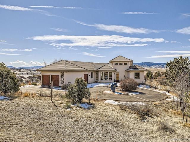 view of front of home featuring a garage, a tiled roof, a mountain view, and stucco siding