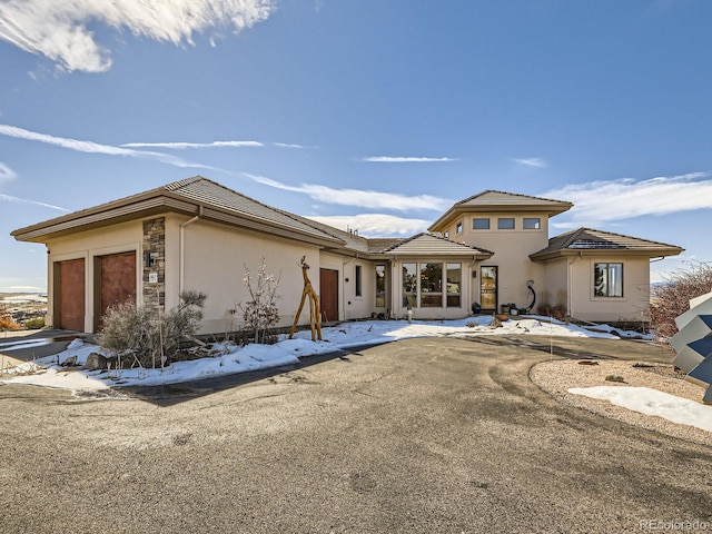 view of front of home featuring a tiled roof, an attached garage, and stucco siding