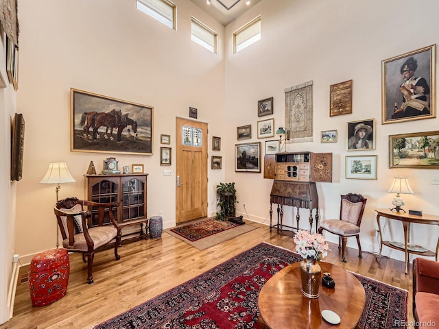 living area with a high ceiling, baseboards, and wood finished floors