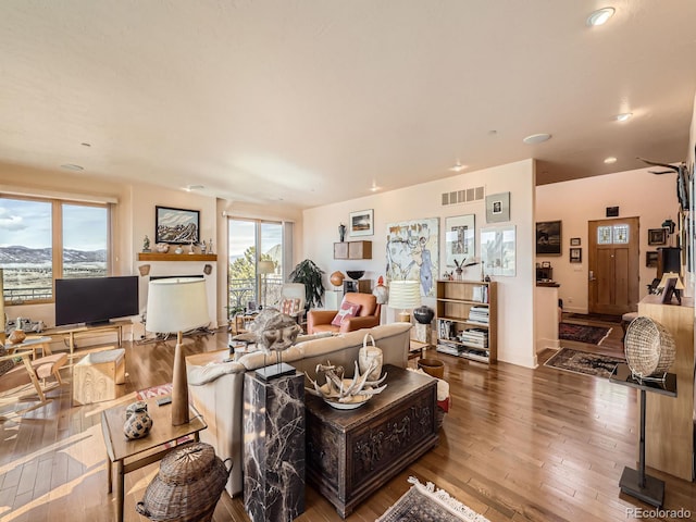 living area with hardwood / wood-style flooring, visible vents, and recessed lighting