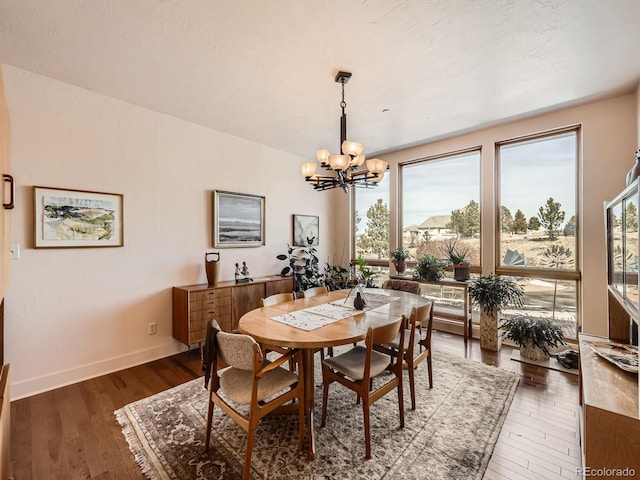 dining area featuring baseboards, hardwood / wood-style floors, and a notable chandelier