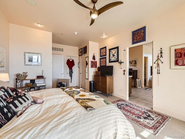 bedroom featuring light tile patterned flooring, ensuite bath, visible vents, and baseboards