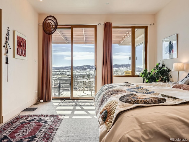 carpeted bedroom with access to exterior, a mountain view, and baseboards