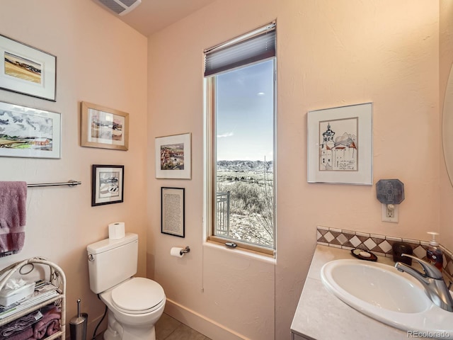 half bath featuring visible vents, baseboards, toilet, tile patterned flooring, and vanity