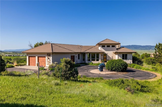8611 Coachlight Way, Littleton, CO 80125 - view of front facade featuring concrete driveway, an attached garage, stucco siding, a tile roof, and a mountain view