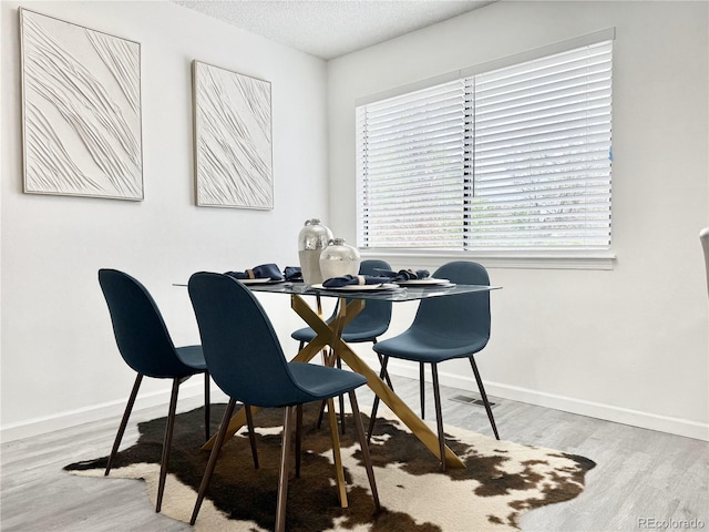180 S Nome St, Aurora, CO 80012 - dining room with wood finished floors, a textured ceiling, and baseboards