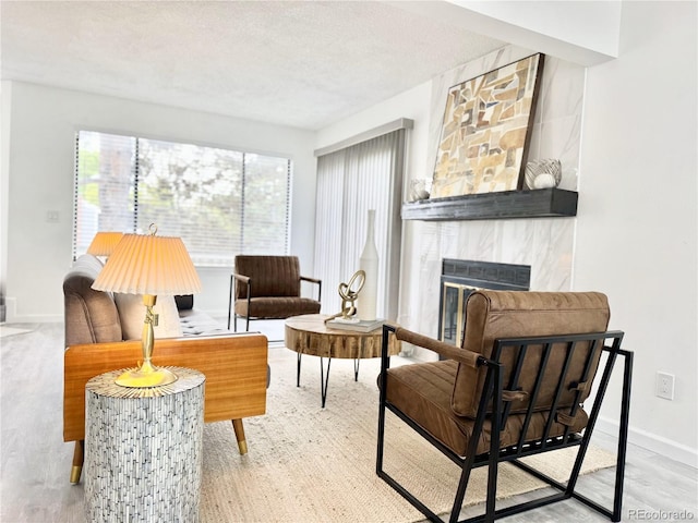 180 S Nome St, Aurora, CO 80012 - sitting room featuring a large fireplace, baseboards, wood finished floors, and a textured ceiling