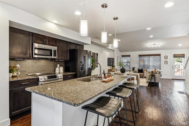 kitchen featuring stainless steel appliances, a sink, dark wood-style floors, a breakfast bar, and dark brown cabinetry
