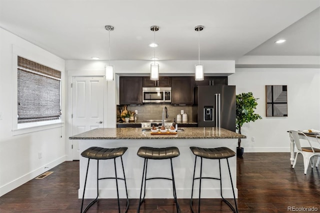 kitchen featuring high quality fridge, stainless steel microwave, a breakfast bar area, baseboards, and recessed lighting
